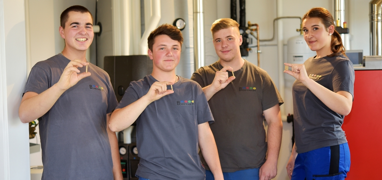 Azubis im Heizungskeller mit Pellets in der Hand