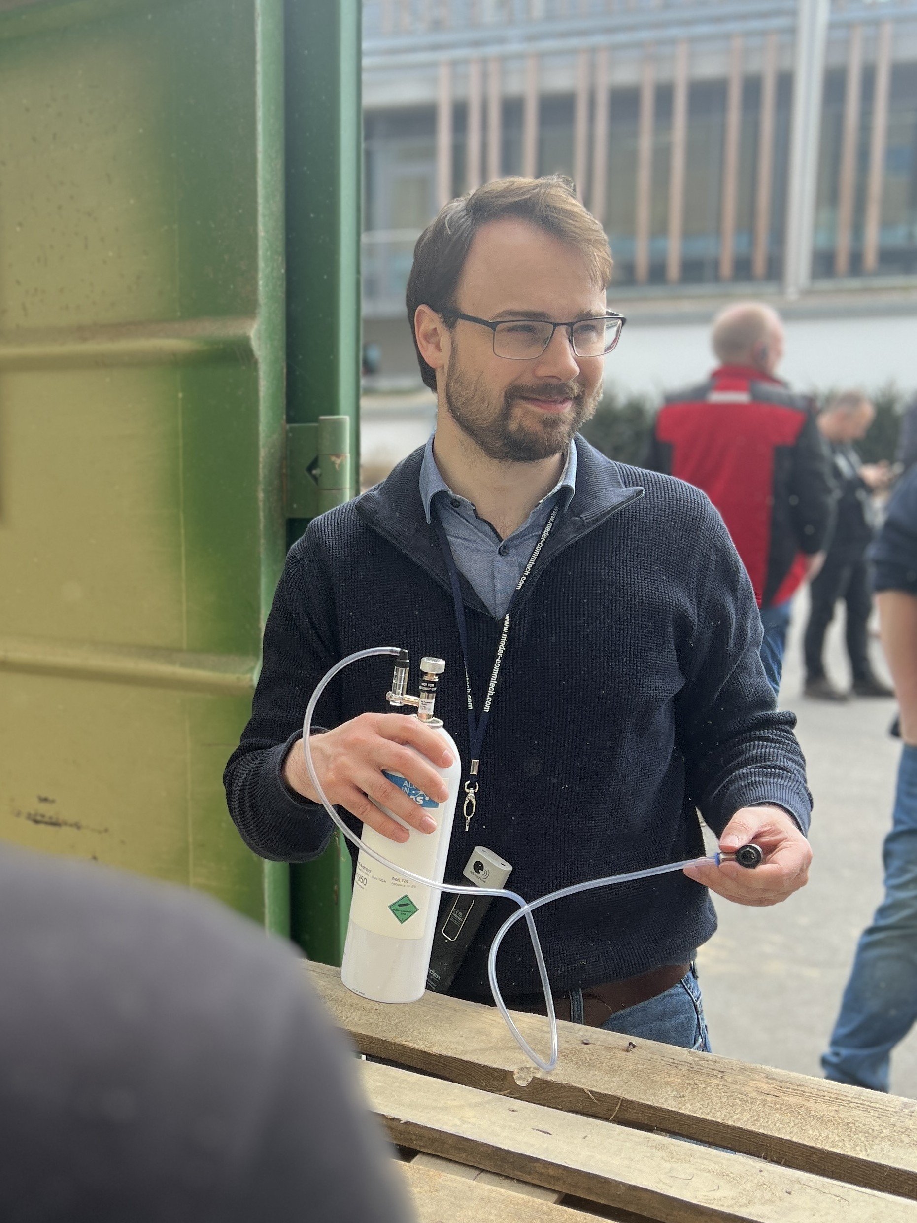 Das Bild im Hochformat zeigt einen Mann, der einen Behaälter mit CO in der Hand hält.