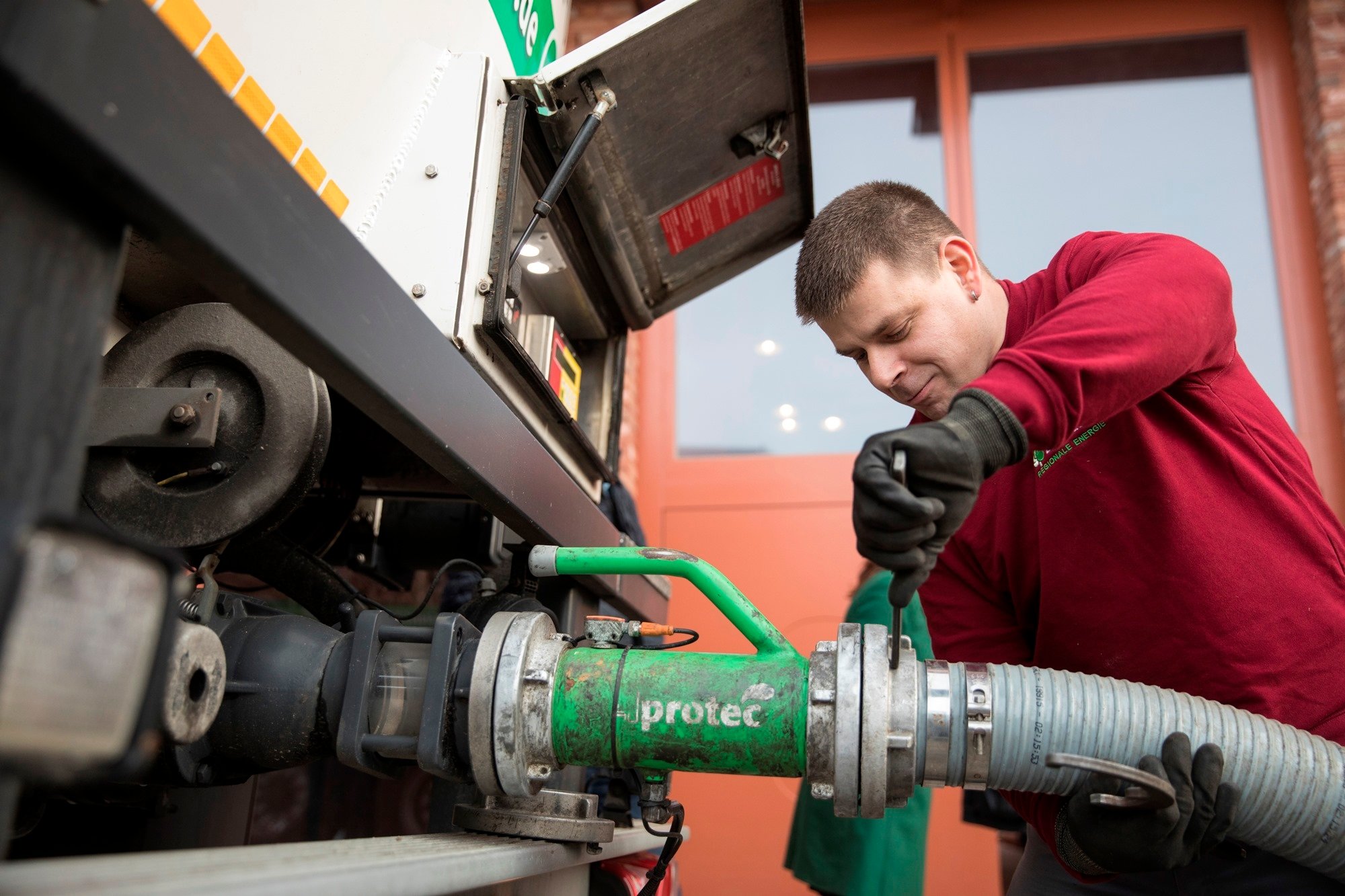 Befüllvorgang: Mann befestigt einen dicken Schlauch mit Gewinde an einem passenden Gewinde am LKW