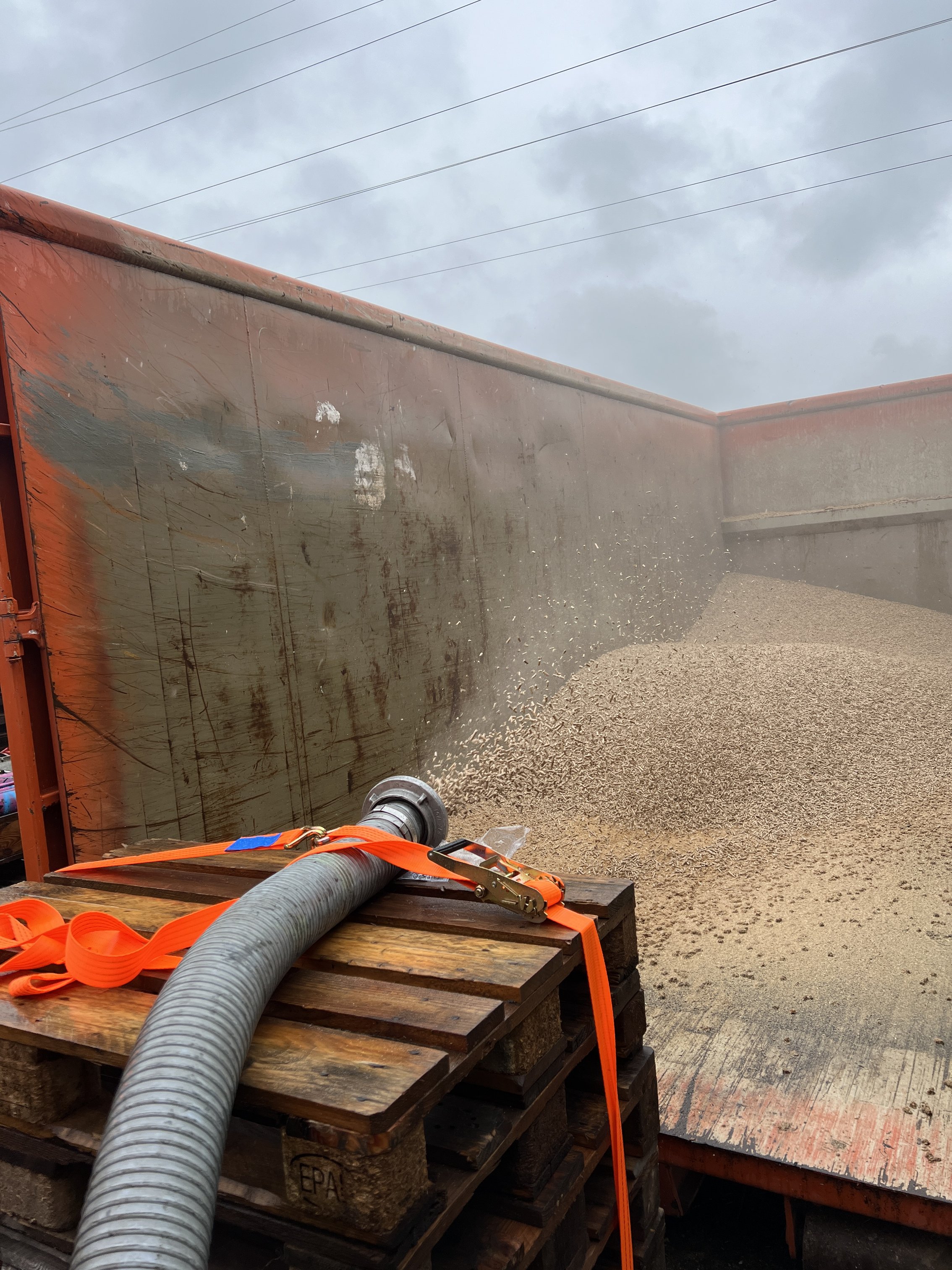 Das Bild im Hochformat zeigt einen Lkw, der mit Pellets aus einem Schlauch gefüllt wird.