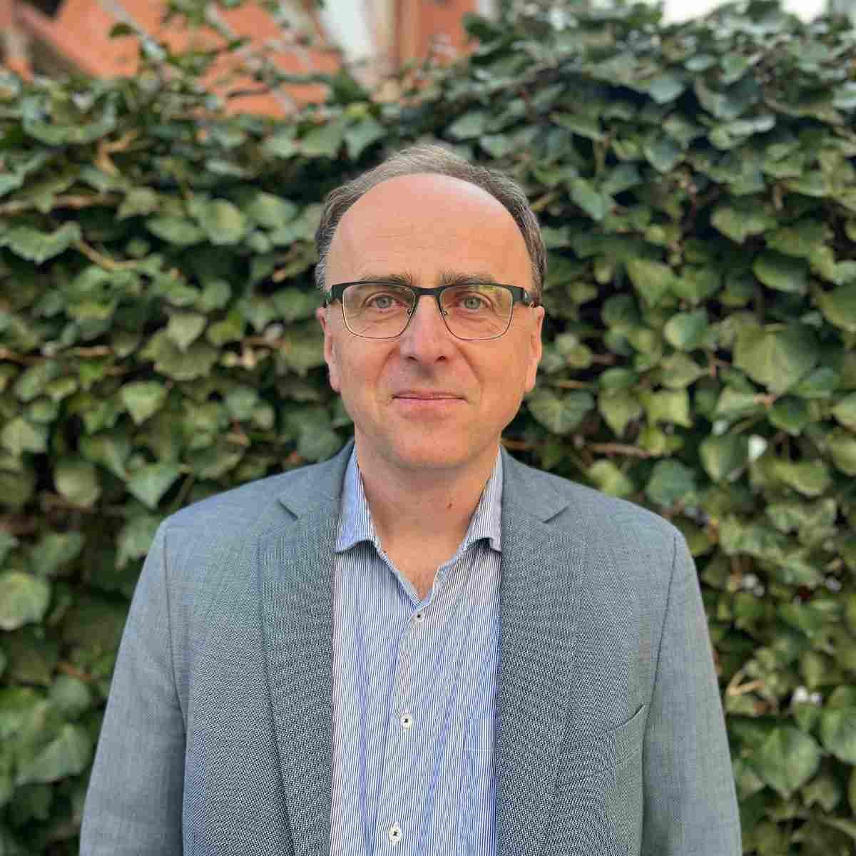 Das Bild zeigt den DEPV Mitarbeiter Hans Martin Behr vor einem grünen Efeu Hecke.