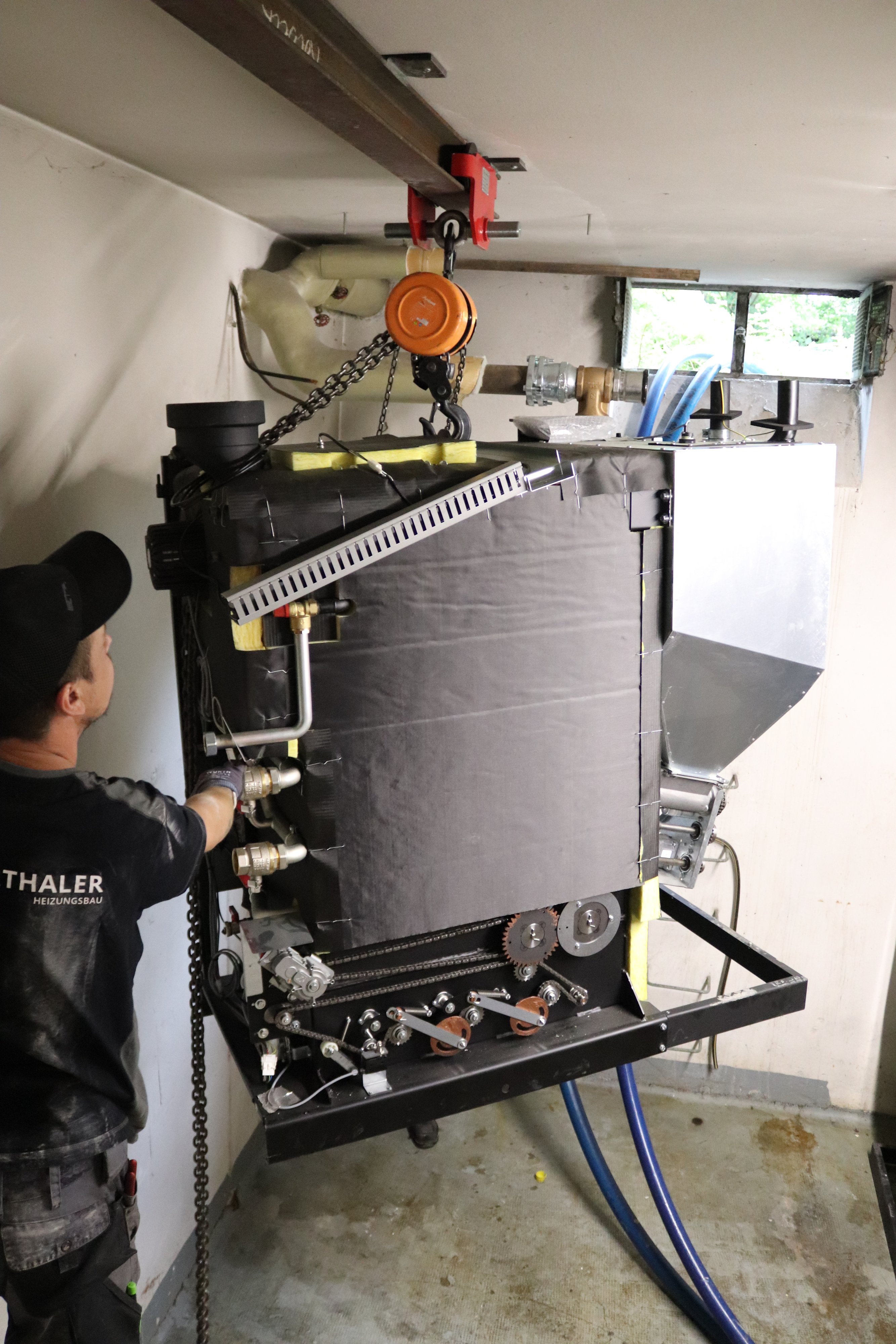 Das Bild zeigt ein technisches schwarzes Gerät bei einer Pelletlieferung davor ist ein Fachmann zu sehen.