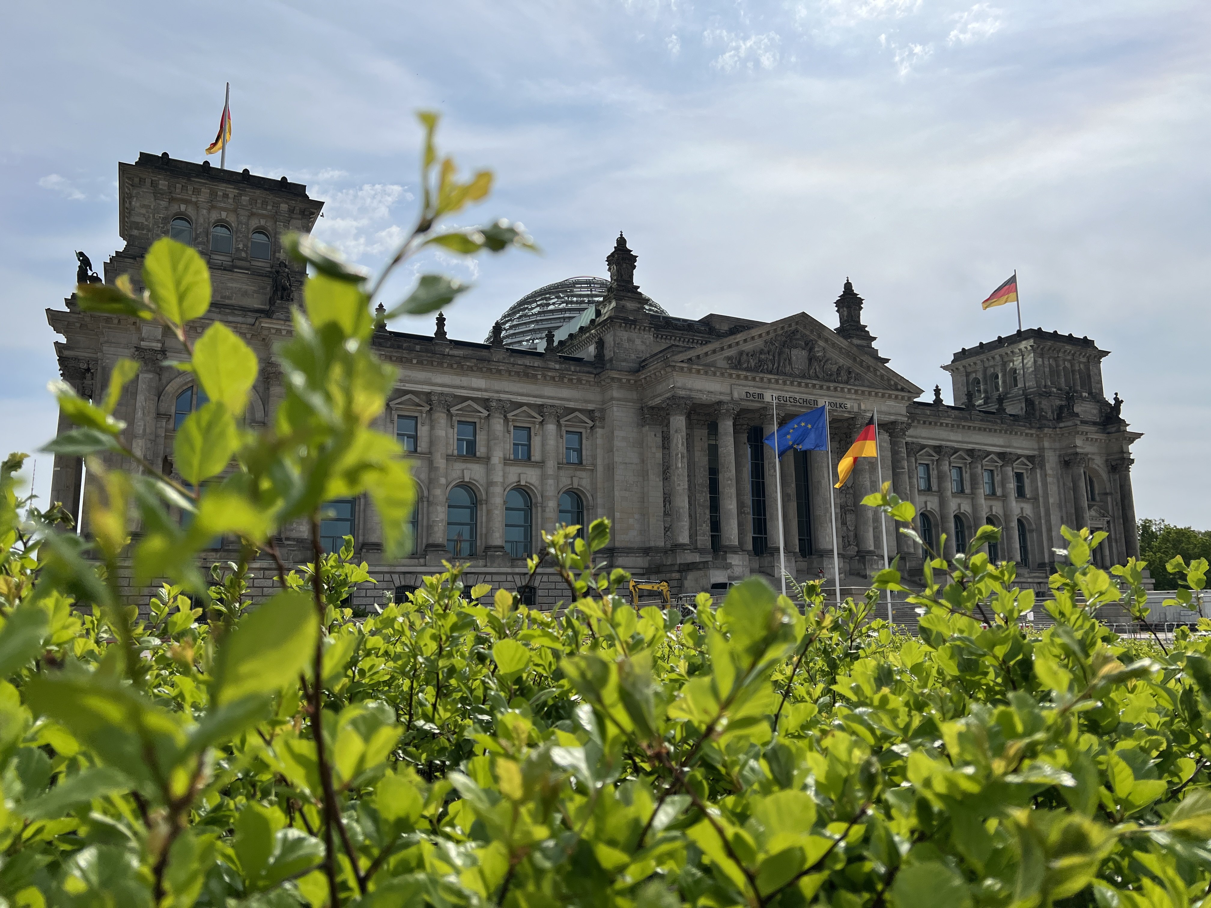 Bild im Querfomat zeigt das Reichstagsgebäude, davor eine grüne üppige Wiese.